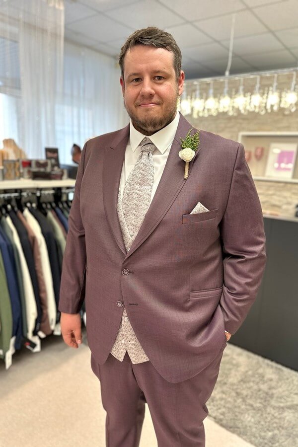 Bräutigam in großer Größe trägt klassischen bordeauxroten Anzug mit roséfarbener Weste und Fliege – elegante Hochzeitsmode bis 7XL bei Biancas Brautmoden
