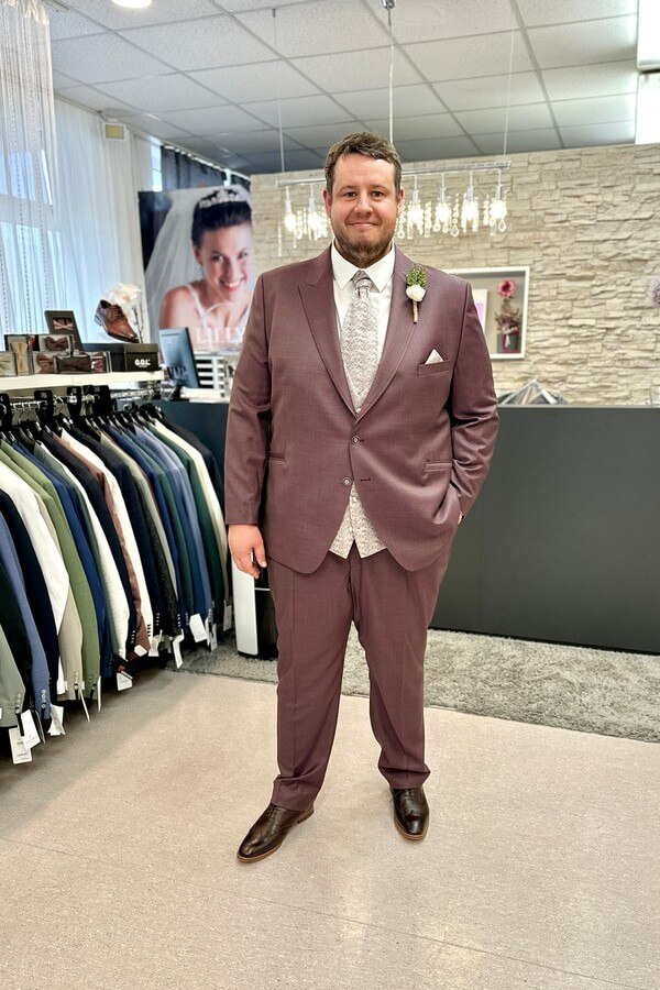 Bräutigam in großer Größe trägt klassischen bordeauxroten Anzug mit roséfarbener Weste und Fliege – elegante Hochzeitsmode bis 7XL bei Biancas Brautmoden