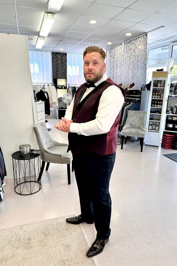 Bräutigam in Übergröße trägt bordeauxroten Smoking mit schwarzem Revers – festliche Herrenmode bis 7XL bei Biancas Brautmoden