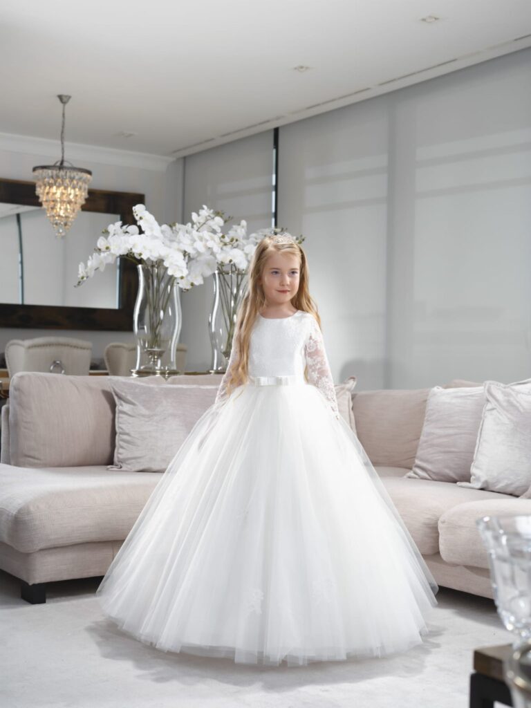 Kommunion 36 Kommunionkleid Bajabella K240 mit Spitzenärmeln und Tüllrock – elegantes Kommunionkleid 2026, erhältlich bei Bianca’s Brautmoden Bad Münster.