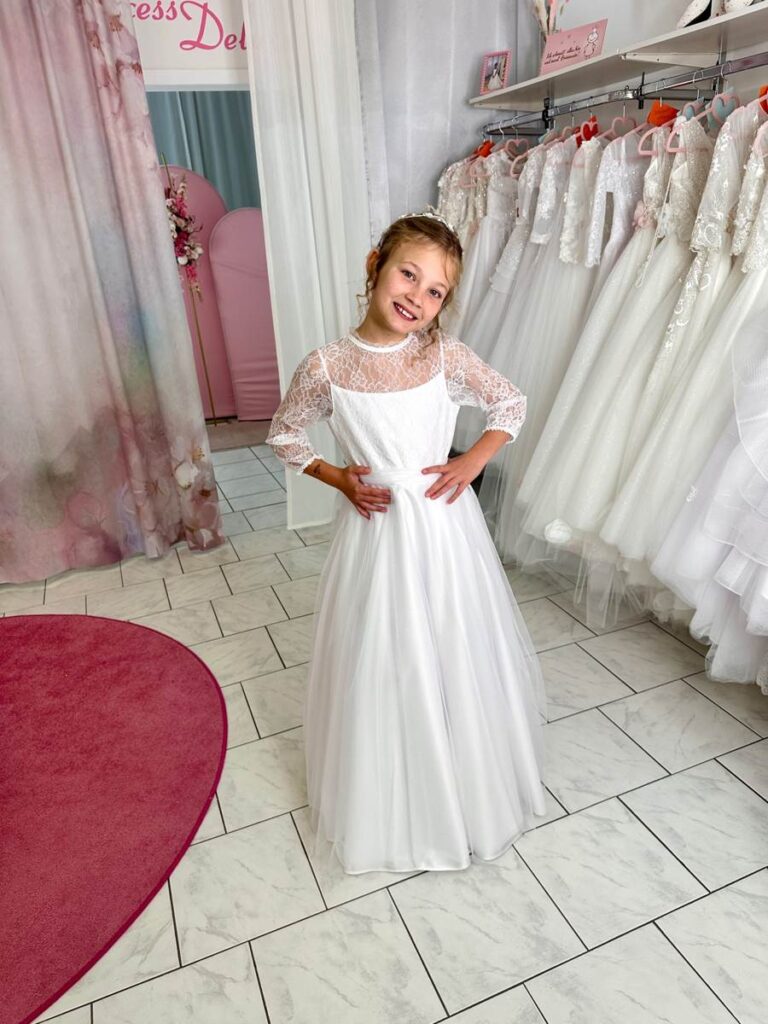 Kommunion 47 Kommunionkleid 2026 in Weiß mit Spitzenoberteil und Tüllrock – elegantes Kleid im italienischen Stil aus eigener Kollektion von Bianca’s Brautmoden Bad Münster.