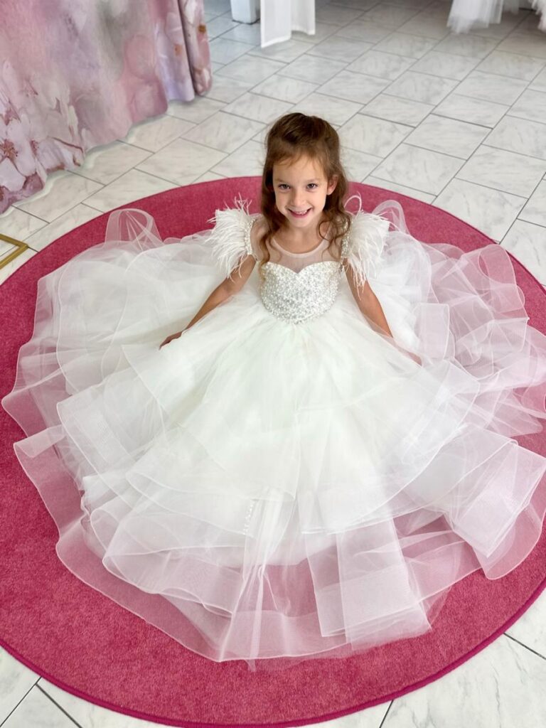 Kommunion 7 Kommunionkleid mit weitem Tüllrock, Perlenoberteil und Federträgern – exklusives Prinzessinnenkleid für Kommunion 2026, erhältlich bei Bianca’s Brautmoden Bad Münster.