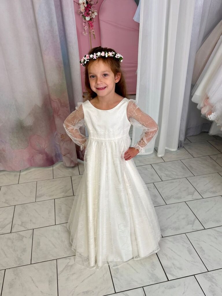 Kommunion 44 Kommunionkleid von Bianco Evento in Ivory mit Jacquardstoff und Spitzenärmeln – elegantes Langarmkleid für Kommunion 2026, erhältlich bei Bianca’s Brautmoden Bad Münster.