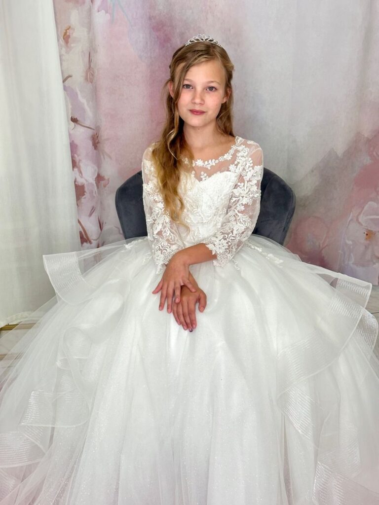 Kommunion 5 Kommunionkleid mit Spitzenoberteil und glitzerndem Volantrock – elegantes Prinzessinnenkleid für Kommunion 2026, erhältlich bei Bianca’s Brautmoden Bad Münster.