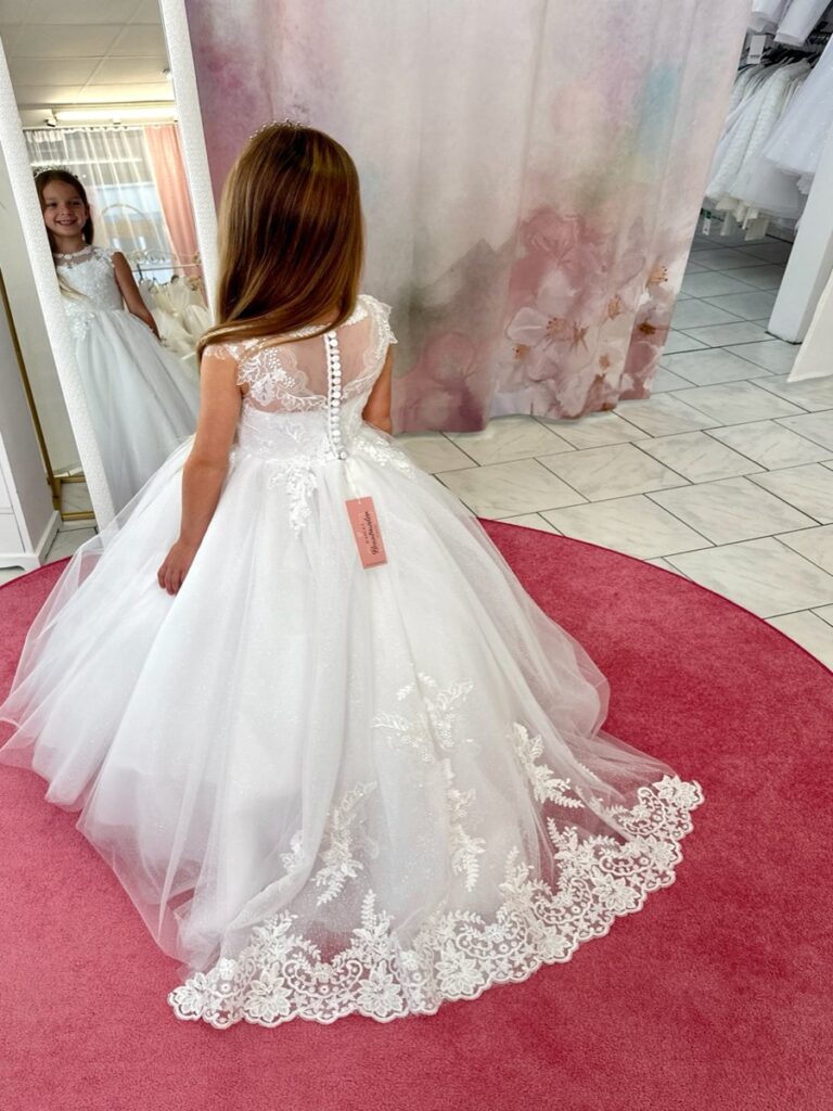 Kommunion 3 Kommunionkleid in Weiß mit Spitze, Knopfleiste und Schleppe – elegantes Prinzessinnenkleid für Kommunion 2026, erhältlich bei Bianca’s Brautmoden Bad Münster.