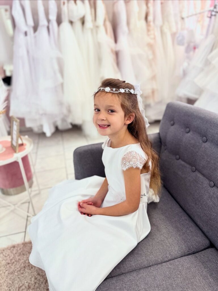 Kommunion 39 Kommunionkleid in Weiß mit Spitzenärmeln und Satinrock – elegantes Kommunionkleid 2026 mit Haarkranz, erhältlich bei Bianca’s Brautmoden Bad Münster.