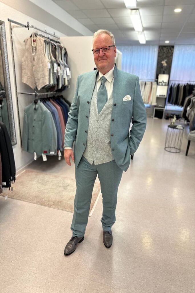 Mann im grünen Anzug von Tziacco mit Stehkragen und Weste in Übergröße