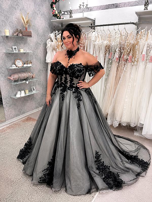 Curvybraut in einem außergewöhnlichen schwarzen Brautkleid mit floraler Spitze, schulterfreiem Ausschnitt und langer Schleppe.