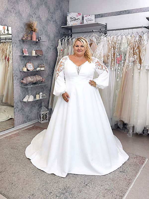 Curvybraut in einem schlichten Brautkleid mit langen Ärmeln aus Spitze, fließendem Rock und schmeichelnder A-Linie.