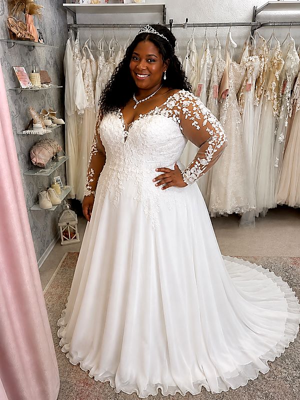 Curvybraut in einem eleganten Brautkleid mit langen Spitzenärmeln, fließendem Chiffonrock und schmeichelnder A-Linie.
