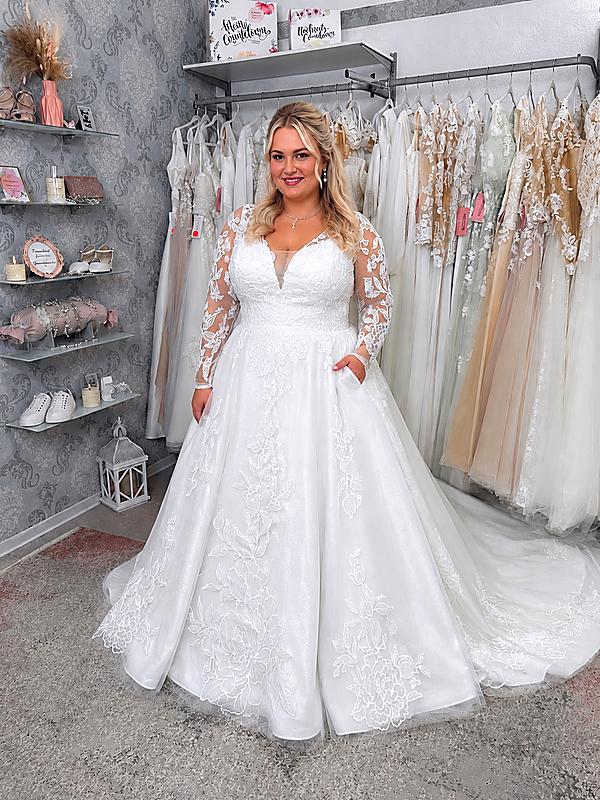 Curvybraut in einem Brautkleid mit langen Spitzenärmeln, Taschen, A-Linie und figurfreundlicher Passform für einen großen Busen.
