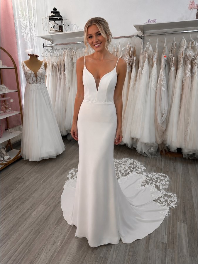 Eine Braut trägt ein cleanes Fit-and-Flare-Brautkleid, das durch seine schlichte Eleganz und den figurbetonten Schnitt begeistert