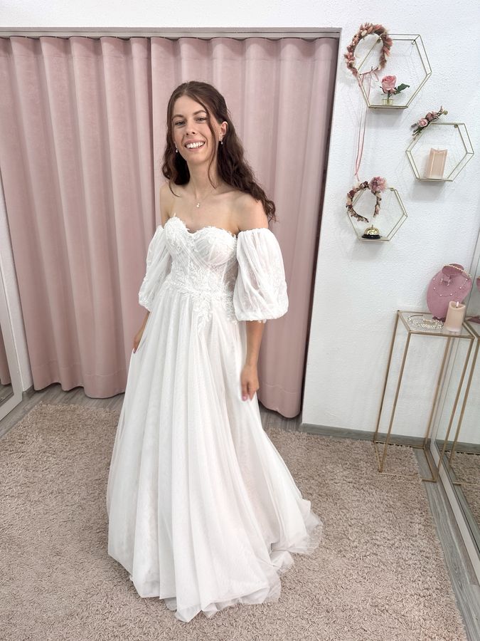 Brautkleid Off Shoulder in leicht fließendem Tüll. Passend dazu große Armstulpen