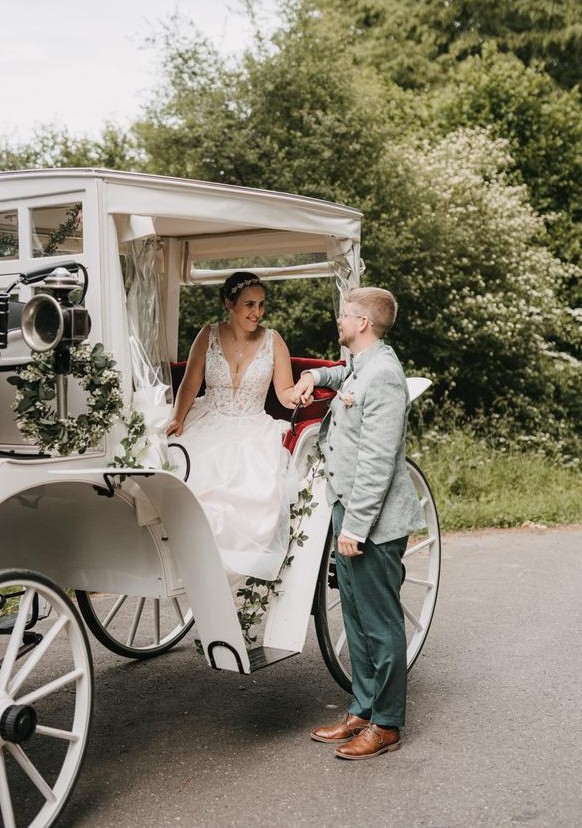 Brautpaar mit Kutsche an ihrer Hochzeit.