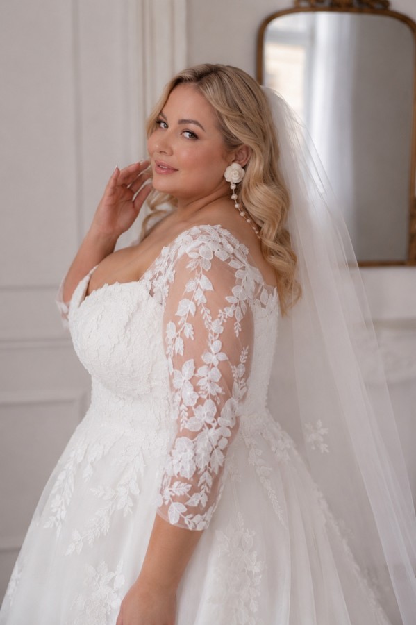 Detailaufnahme eines Curvy Brautkleids mit floralen Spitzenärmeln, Herzausschnitt und Schleier aus der Kollektion 2027 bei Bianca's Brautmoden Bad Kreuznach