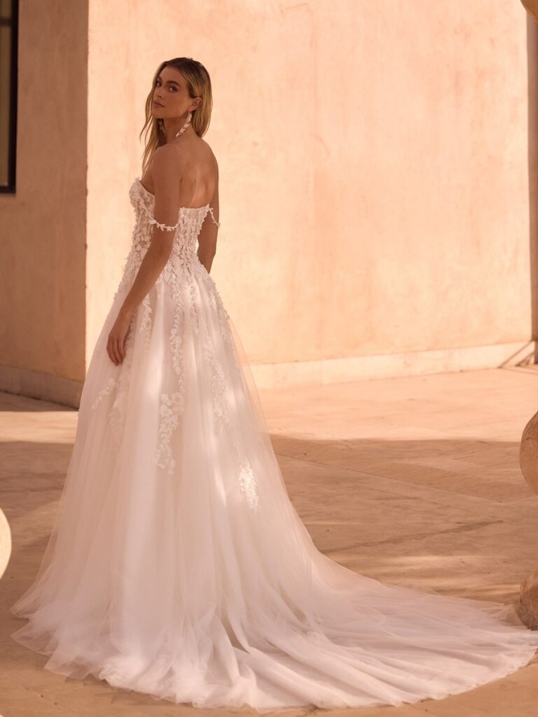 Romantisches A-Linien-Brautkleid mit floraler 3D-Spitze, Off-Shoulder-Ausschnitt, zarten Trägern und tiefem Rückenausschnitt. Der fließende Tüllrock mit langer Schleppe verleiht dem Hochzeitskleid eine elegante und märchenhafte Ausstrahlung.