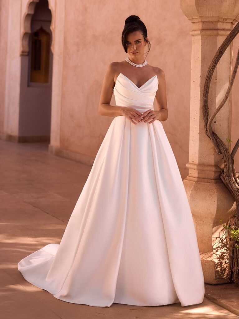 Cleanes A-Linien-Brautkleid aus Mikado mit herzförmigem Ausschnitt, drapiertem Oberteil und langer Schleppe. Das schlichte Hochzeitskleid überzeugt durch zeitlose Eleganz und eine moderne Silhouette.