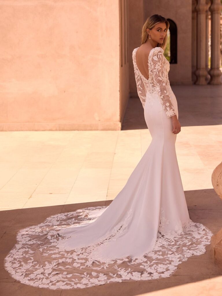 Braut mit figurbetonten Meerjungfrauen-Brautkleid mit cleanem Crepe-Rock, tiefem V-Ausschnitt, langen Spitzenärmeln und floraler 3D-Spitze am Oberteil