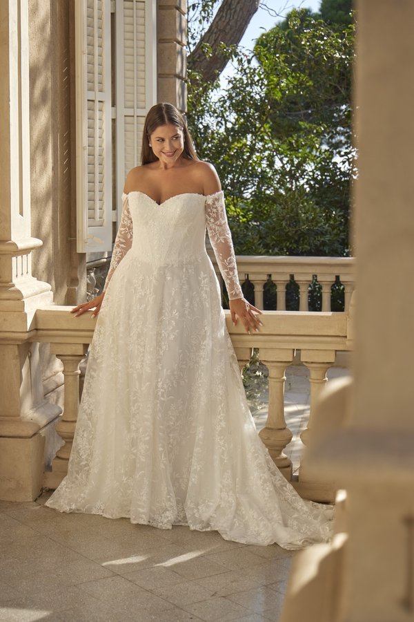 Curvy Brautkleid in A-Linie mit Carmen-Ausschnitt, langen Spitzenärmeln und floraler Spitze aus der Kollektion 2027 bei Bianca's Brautmoden Bad Kreuznach