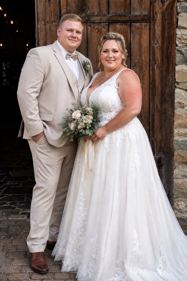 Kräftiges Brautpaar an ihrem Hochzeitstag in einem beigen Anzug und sie in einem romantischen Tüllkleid mit breiten Trägern
